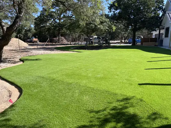 Wide artificial turf lawn in a backyard with oak trees
