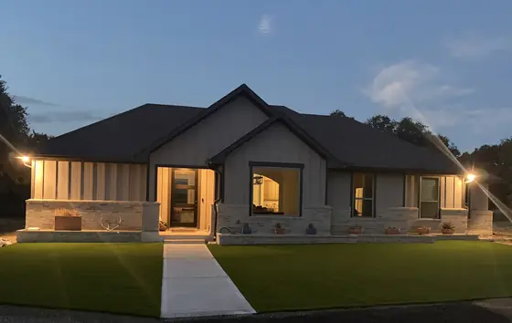 Front yard of a single-story home at dusk with freshly installed artificial turf on both sides of the walkway
